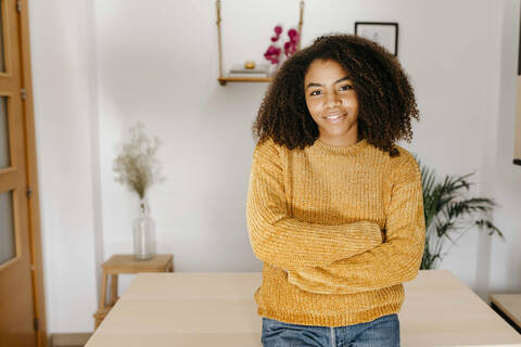 Curly hair woman standing with arms crossed at home stock photo