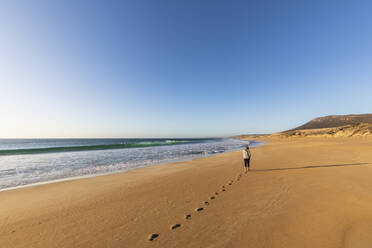 Klarer Himmel über einer Frau, die allein am Greenly Beach spazieren geht - FOF11992