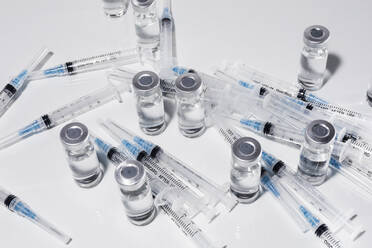 Syringes and COVID-19 vaccine vials on white background - FSIF05594