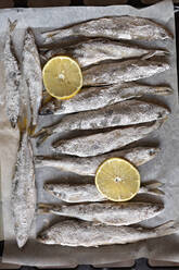 Salted whole fish and lemon slices on parchment paper - FSIF05602