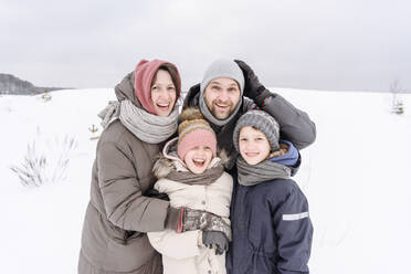 Happy family standing on snow covered land against sky during vacation - EYAF01459