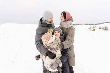 Familie genießt Urlaub auf schneebedeckten Landschaft gegen den Himmel - EYAF01463