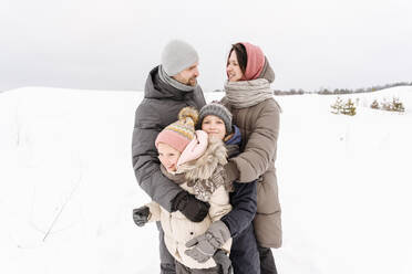 Family enjoying vacation on snow covered landscape against sky - EYAF01463