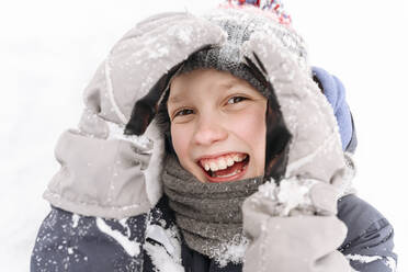 Nahaufnahme eines fröhlichen Jungen, der mit Schnee spielt - EYAF01468