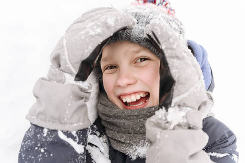 Close-up of cheerful boy playing with snow - EYAF01468