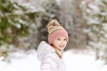Lächelndes Mädchen in warmer Kleidung im Winter im Wald stehend - EYAF01485