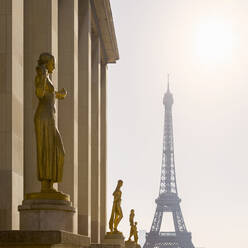 Frankreich, Ile-de-France, Paris, Goldene Statuen des Palais de Chaillot mit Eiffelturm im Hintergrund - AHF00277