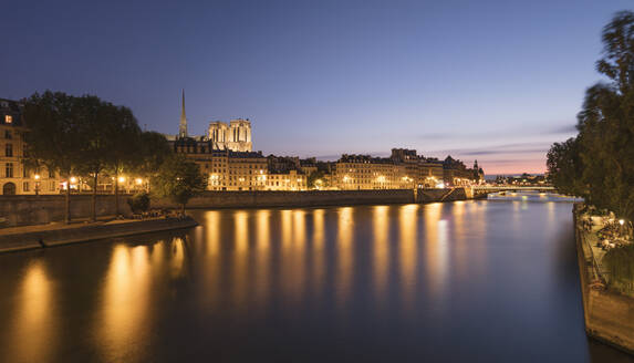 Frankreich, Ile-de-France, Paris, Langzeitbelichtung des Seine-Kanals in der Abenddämmerung mit Wohnhäusern und Notre-Dame de Paris im Hintergrund - AHF00303