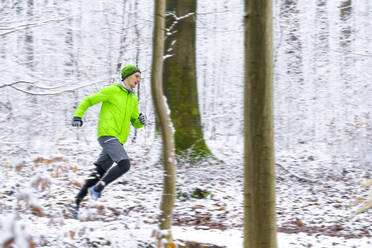 Junger männlicher Sportler, der im Winter im Wald läuft - STSF02786