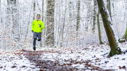 Junge männliche Sportlerin beim Joggen im Winter im Wald - STSF02790