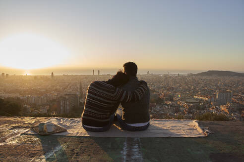 Gay boyfriends looking at cityscape against clear sky while sitting on observation point, Bunkers del Carmel, Barcelona, Spain - VEGF03619