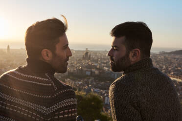 Romantisches schwules Paar, das sich gegenseitig ansieht, mit Stadtbild im Hintergrund, Bunkers del Carmel, Barcelona, Spanien - VEGF03622