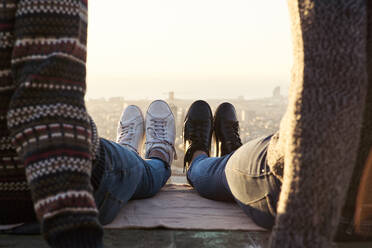 Beine eines schwulen Paares mit Schuhen, das auf einem Aussichtspunkt sitzt, Bunkers del Carmel, Barcelona, Spanien - VEGF03626