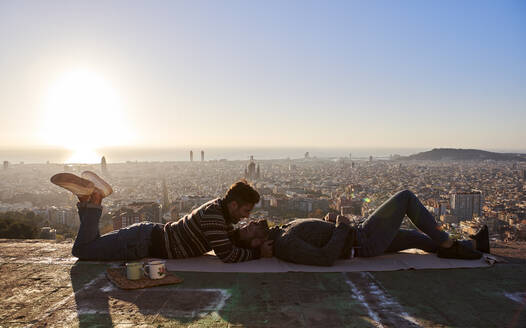 Schwule Männer, die während des Sonnenaufgangs auf dem Aussichtspunkt liegen, Bunkers del Carmel, Barcelona, Spanien - VEGF03637