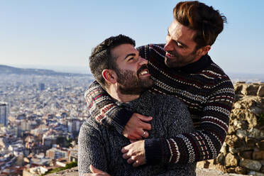 Romantische schwule Männer, die sich gegen den klaren Himmel ansehen, Bunkers del Carmel, Barcelona, Spanien - VEGF03654