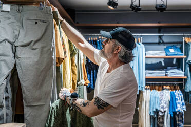 Side view of man choosing clothes in a clothing store - ADSF20321