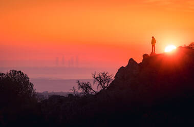 Fernaufnahme eines nicht erkennbaren Touristen, der auf einem Felsen steht und die Aussicht auf Madrid bei Sonnenuntergang genießt - ADSF20347