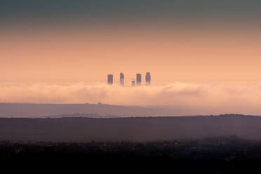 Erstaunlicher Blick auf die Skylines des Geschäftsviertels Cuatro Torres, umgeben von dicken Wolken bei Sonnenuntergang in Madrid - ADSF20350