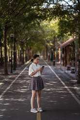 Asiatische Frau mit Smartphone und zu Fuß auf dem Tanya Shen Green Bikeway in Taichung - ADSF20369