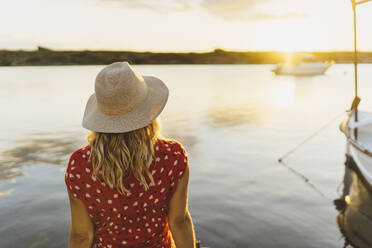 Woman wearing hat admiring view during sunset - DGOF01839