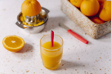 Glas Orangensaft mit Löffel und Saftpresse aus Edelstahl auf modernem Marmor - GEMF04585