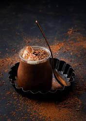 Von oben leckere Mousse au Chocolat in einem Glasgefäß, das mit Schokoladenpulver bestäubt auf dem Tisch steht - ADSF20438