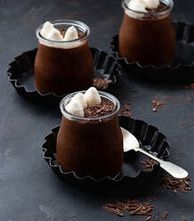 Tasty chocolate mousse in glass jar arranged on table with chocolate powder dust - ADSF20439