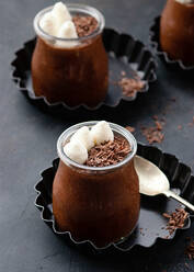 Von oben leckere Mousse au Chocolat in einem Glasgefäß, das mit Schokoladenpulver bestäubt auf dem Tisch steht - ADSF20440
