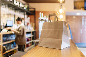 Essen zum Mitnehmen, das während der Pandemie in einer braunen Papiertüte auf der Theke aufbewahrt wurde - DGOF01859