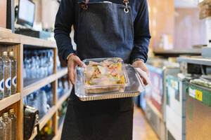 Reifer männlicher Manager hält Folie und Plastikbehälter bei der Arbeit im Restaurant - DGOF01868