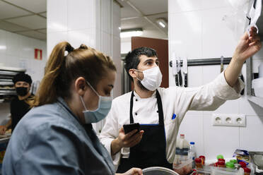 Male and female chef working in commercial kitchen during COVID-19 - DGOF01889