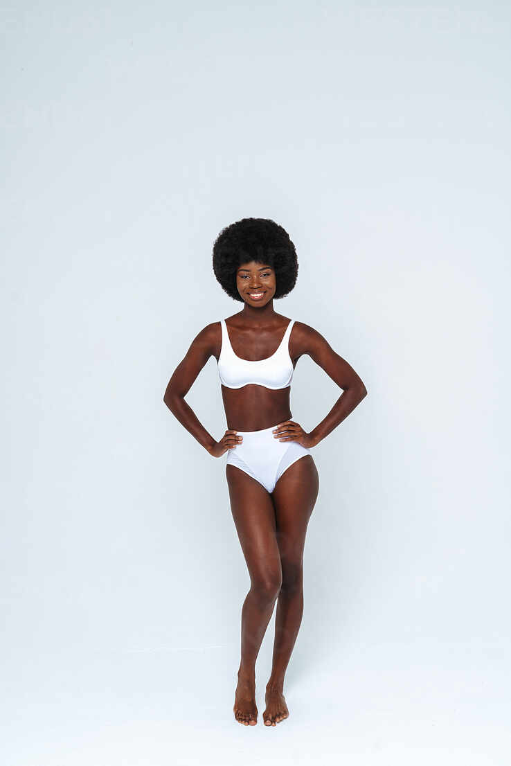 Skinny female model wearing bikini standing against white background stock  photo