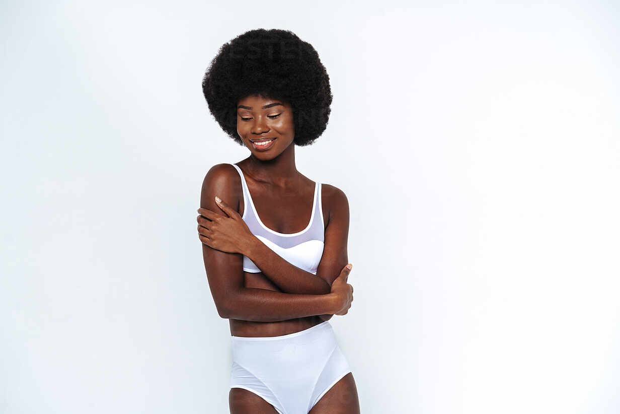 Afro-American skinny woman wearing lingerie with arms crossed posing  against white background stock photo