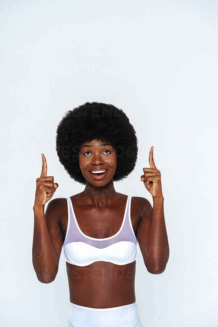 Afro-American skinny woman wearing lingerie pointing while standing against  white background stock photo