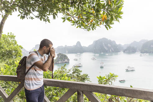 Männlicher Tourist mit Rucksack beim Fotografieren der Halong-Bucht in Vietnam - WPEF03956