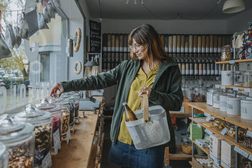 Frau mit Brille und Korb beim Einkaufen in einem Zero-Waste-Shop - MFF06943
