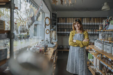 Smiling saleswoman with arms crossed standing in zero waste store - MFF06947