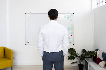 Male professional standing in front of whiteboard while working in office - GIOF10881