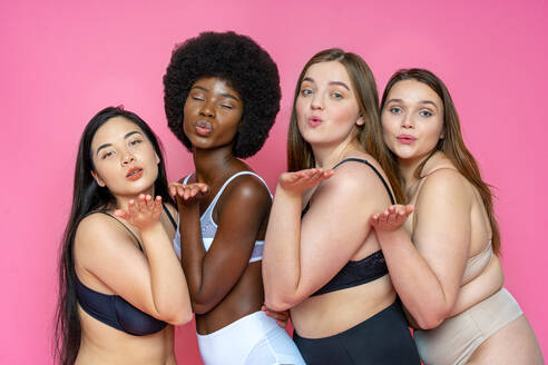 Multi-ethnische Gruppe von weiblichen Modellen in Dessous bläst Küsse vor rosa Hintergrund - OIPF00143