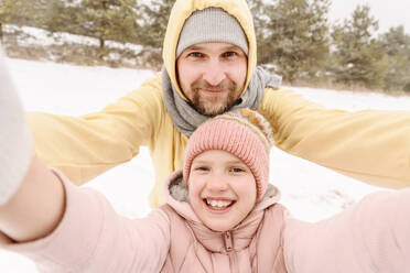 Nahaufnahme eines lächelnden Vaters und einer lächelnden Tochter in einer verschneiten Landschaft - EYAF01500