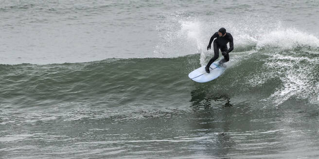 Älterer Mann beim Surfen auf dem Meer am Manorbier Beach, Wales, UK - ALRF01825