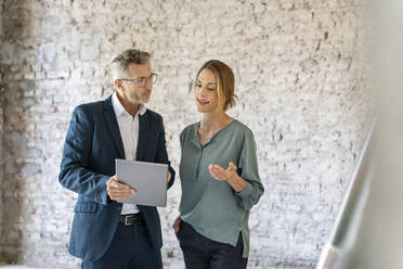 Businesswoman having discussion with architect while working over digital tablet at construction site - PESF02555