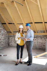 Professional team wearing hardhat working while standing with digital tablet at construction site - PESF02599