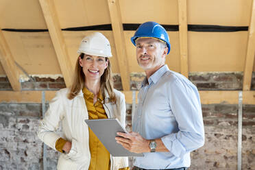 Confident expertise team smiling while standing with digital tablet at construction site - PESF02603