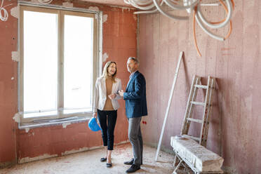 Male engineer and businesswoman working together while examining construction site - PESF02611