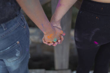 Lesbian couple with colorful powder paint holding hands - SNF01043