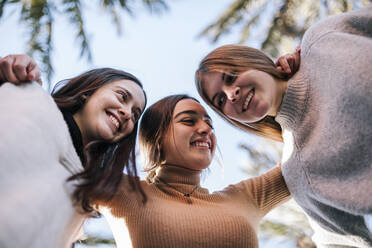 Lächelnde Freundinnen kuscheln sich im Park an den klaren Himmel - GRCF00654