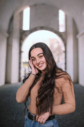 Smiling teenage girl with long hair standing on footpath in tunnel - GRCF00665