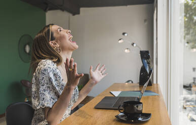 Geschäftsfrau lachend bei der Arbeit am Tisch im Café - DSIF00281