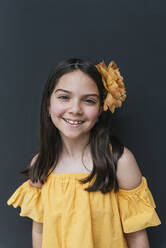Lächelndes Mädchen mit gelbem Oberteil und Stirnband vor schwarzem Hintergrund - DSIF00298